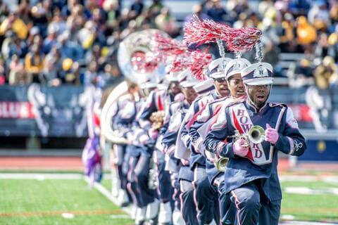 Howard marching band performing with a crowd cheering in the stands